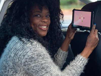 Rideshare passenger playing with octopus tablet in back seat of car